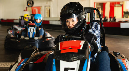 Fototapeta na wymiar young happy woman driving racing car at kart circuit