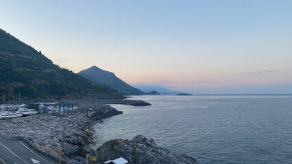 Landscape of the south of Italy from a boat at sunset with high hills, sea till the line of the horizon with past colour in a sunny day