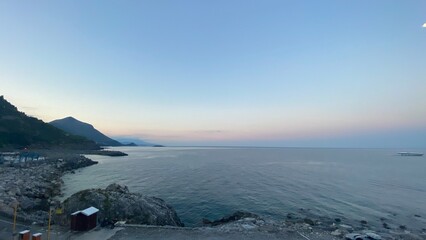 Landscape of the south of Italy from a boat at sunset with high hills, sea till the line of the horizon with past colour in a sunny day