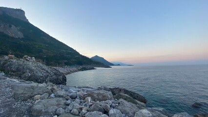 Landscape of the south of Italy from a boat at sunset with high hills, sea till the line of the horizon with past colour in a sunny day