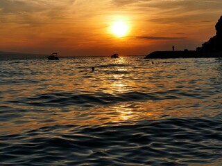 Beautiful orange sunset with waves and dark silhouettes