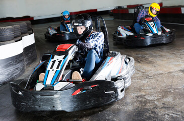 Young sportive people driving sport cars for karting in a circuit lap in sport club - obrazy, fototapety, plakaty