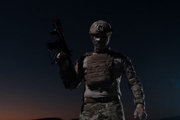 Army soldier in Combat Uniforms with an assault rifle, plate carrier and combat helmet going on a dangerous mission on a rainy night. 