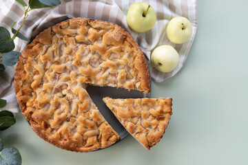 Homemade apple pie on a table in a gray plate with yellow apples and a kitchen towel. Top view...