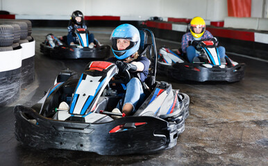 Portrait of female racer in helmet driving kart on track © JackF