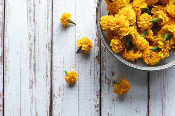 Harvested Marigold flowers in strainer on wooden table, overhead flay lay, copy space