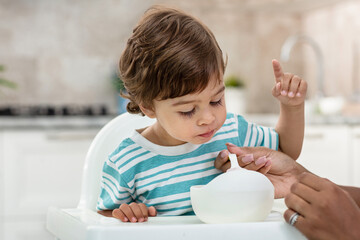 A Black Young mother feeding her baby son with fruit puree