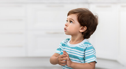 A small child looks up sitting on the floor in a room