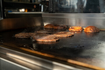 Make burgers on the grill restaurant. Burgers cooking on a gas grill, how to make a burger step by step. A person using a spatula to cut meat. a person cutting meat on a grill with a knife