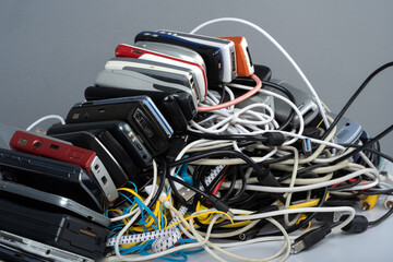 Pile of tangled old smart technology wires, charging cables and used obsolete mobile phones. Old...