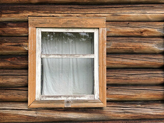 Wall of a wooden log house with a window.