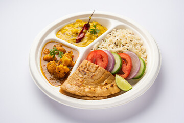 Indian mini meal parcel platter or combo thali with Gobi Masala, roti, dal tarka, jeera rice, salad