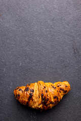 Vertical image of croissants lying on wooden board on dark grey surface
