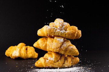 Image of croissants with powder sugar on black background