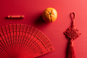 Composition of traditional chinese fan and decorations on red background