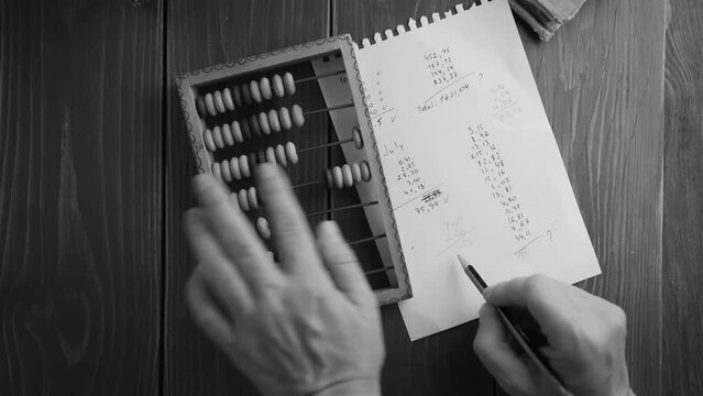 hand making calculations on vintage abacus sliding beads white and black