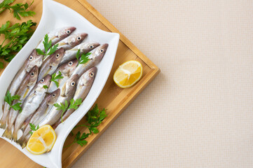 Fresh uncooked haddock fishes on in ceramic dish on table, raw whiting fish concept