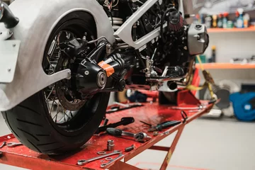 Foto op Plexiglas Motorfiets Aangepaste motorfiets repareren die in reparatiewerkplaats staat. Instrumenten en apparatuur. Hobby& 39 s en unieke banen