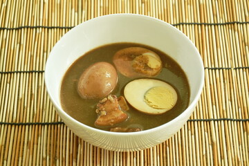 boiled half cut egg with fat pork in herb brown soup on bowl