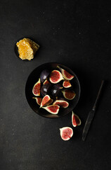 Fresh figs in pieces with honey in a black bowl on a black background