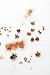 Cinnamon powder and anise star spice background on light surface