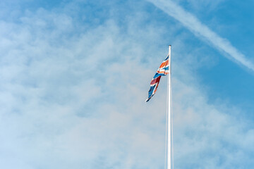 Flag of Great Britain over a light blue sky with some clouds.