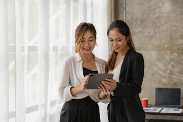 Obraz premium Two beautiful Asian women consulting a collaborative structure using tablets looking at screens for online shopping. internet collaboration concept