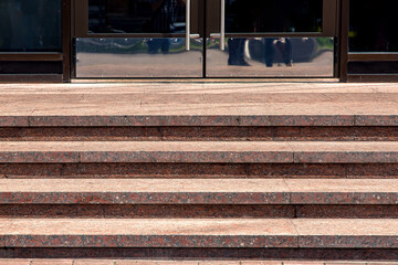 granite staircase with stone steps rise to the entrance front door with stainless steel handle on...