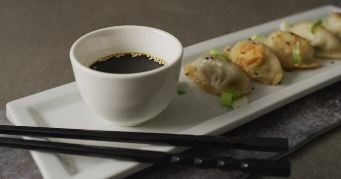 Composition of plate with gyoza dumplings and soy sauce with chopsticks on grey background