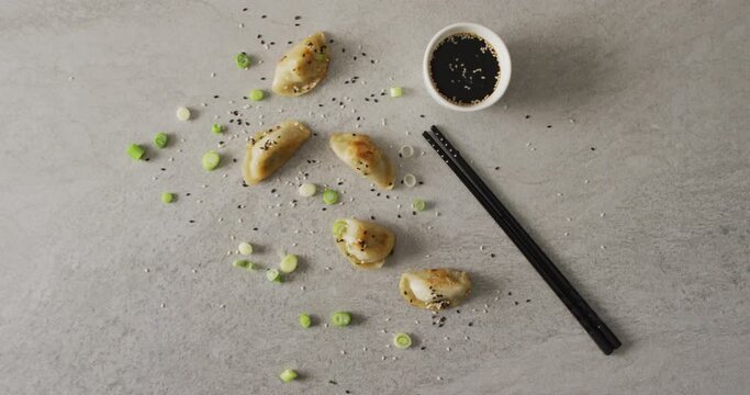 Composition of gyoza dumplings and soy sauce with chopsticks on grey background