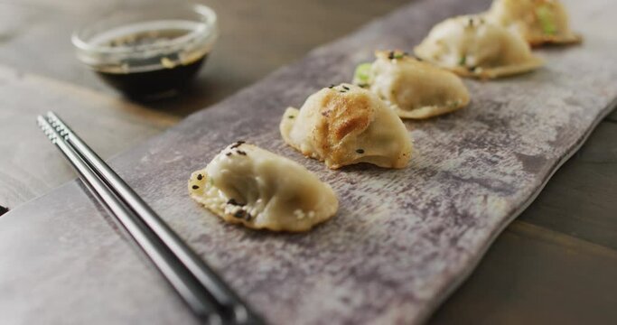 Composition of plate with gyoza dumplings and soy sauce with chopsticks on wooden background