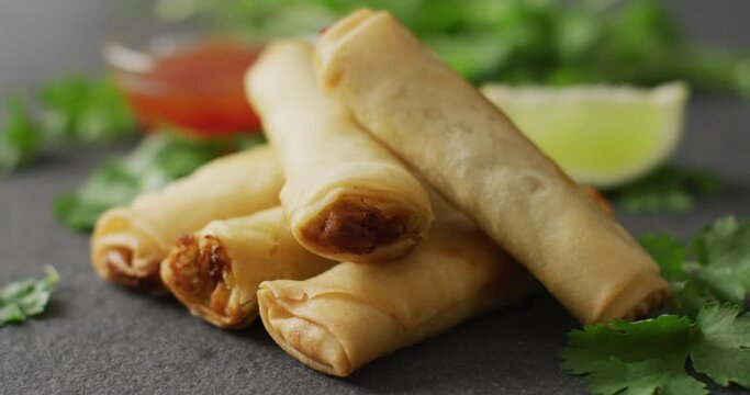 Composition of plate with spring rolls and chilli sauce on black background