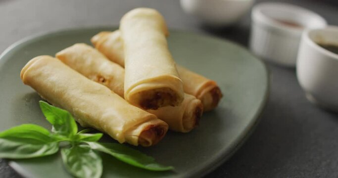 Composition of plate with spring rolls and chilli sauce on grey background