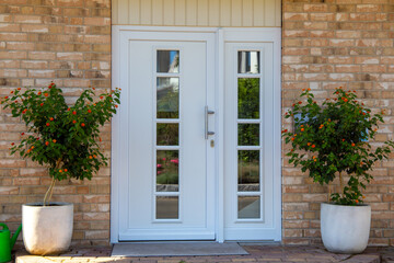 Fototapeta na wymiar Moderne weiße Haustür an einem neuen Wohnhaus mit schöner Klinker-Fassade