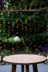 Round wooden table on a green nature with light bulbs background. Outdoor table at desk. Grass,...