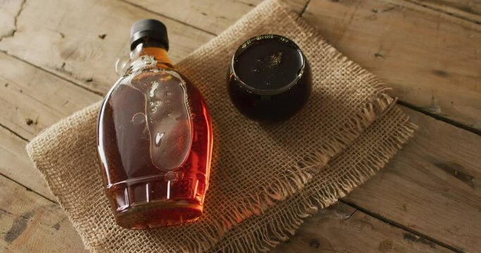 Video of maple syrup in bottle and fabric on wooden surface
