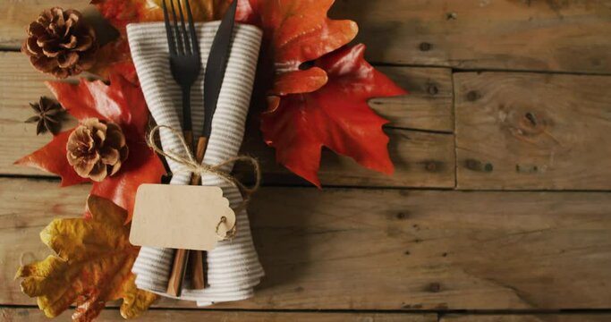 Video of cutlery and autumn leaves lying on wooden surface