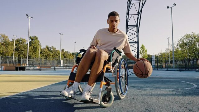 Disabled African American man hits basketball ball on court