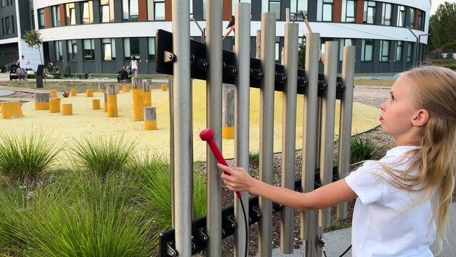 little girl hitting notes on tubular bells with two hammers