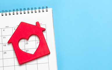 Red House with a heart on the calendar, blue background. Template Copy space for text. mock-up