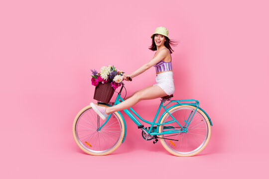 Full length photo of charming impressed lady wear purple bra riding bicycle empty space isolated pink color background