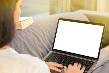 Fototapeta premium Work at home, young brunette woman work at home. Holding modern laptop for mock up, blank white screen. Hands on keyboard typing, browsing, designing, coding. Morning light with copy space area. 