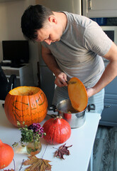 A man makes Jack's lantern out of a large orange pumpkin. Preparation for the celebration of Halloween, the tradition of decorating the house and the street