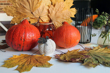 Orange ripe pumpkins, a bouquet of dried flowers and maple leaves, decor for the Halloween holiday. The tradition of decorating the house for the autumn holiday.