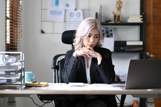 Image of an Asian business woman is stressed, bored, and overthinking from working on a tablet at the office.