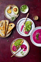 Avocado toast with pink beet hummus spread or dip with edible onion flowers and microgreens. Healthy plant based appetizer, vegan, vegetarian snack