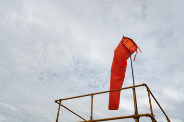Fototapeta na wymiar An orange windsock on rooftop of the industrial plant, it using to identify windy speed and direction. Industrial safety equipment object photo.