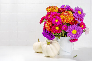 Flowers and pumpkins on white table background. Bouquet of colorful chrysanthemum, peonies with white decoration pumpkins, autumn thanksgiving holiday background copy space