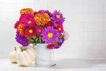 Flowers and pumpkins on white table background. Bouquet of colorful chrysanthemum, peonies with white decoration pumpkins, autumn thanksgiving holiday background copy space