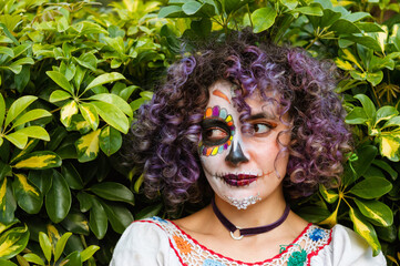 portrait of a woman with catrina makeup looking to the side, with natural green leafy on background